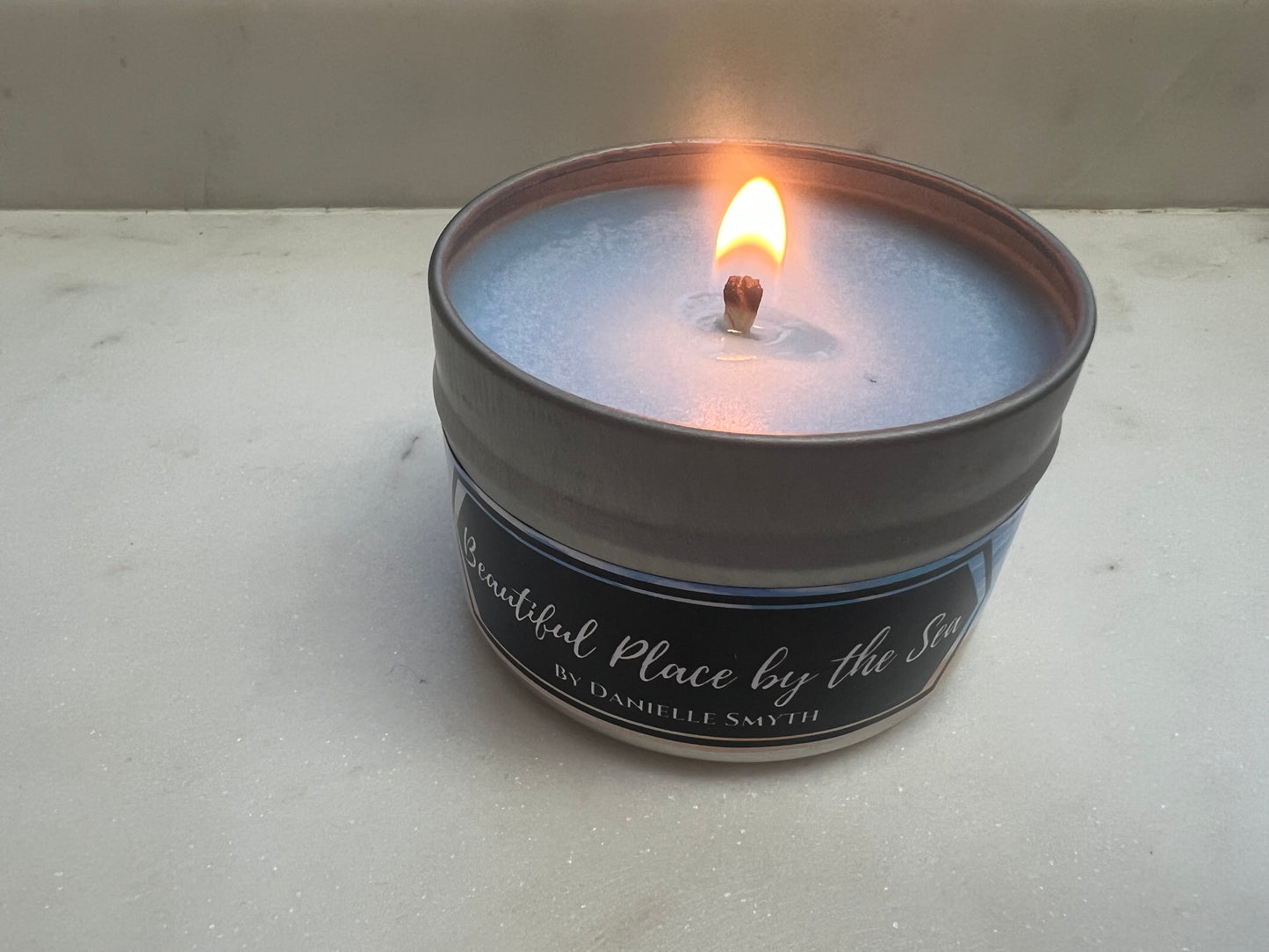 Candle in a tin container with a label on a light gray background